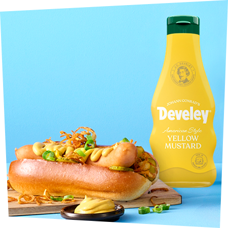 Ein Hotdog mit knusprigen Röstzwiebeln und knackigen Gurken garniert mit dem American Style Yellow Mustard von Develey