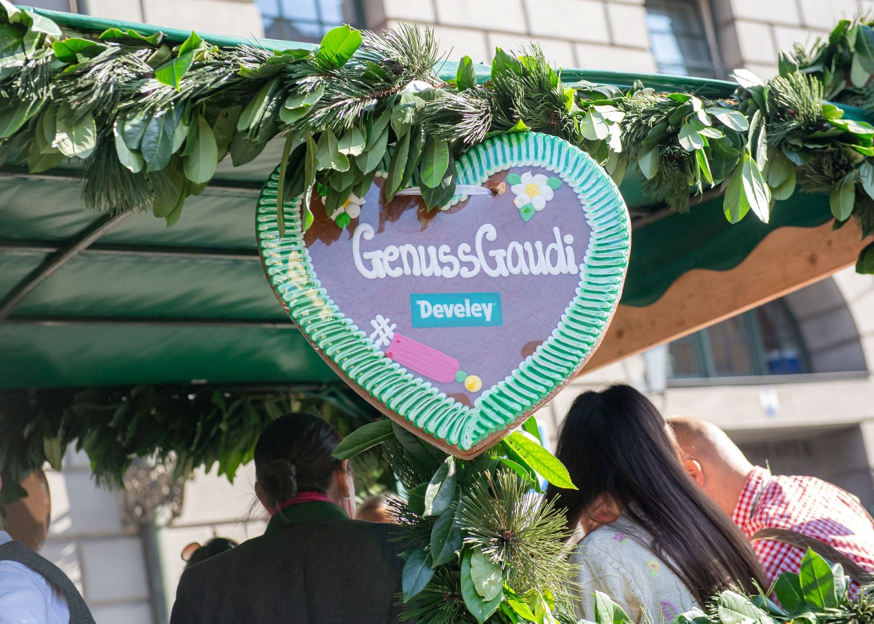 Ein Develey Lebkuchenherz mit der Aufschrift: "Genuss Gaudi" an einem Umzugswagen auf dem Weg zum Oktoberfest