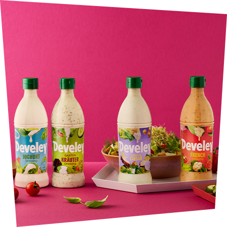 Alle 4 Dressings von Develey mit einer Schüssel frischem Salat