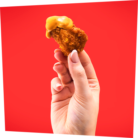 Develey Hand hält Fried Chicken mit Crispy Chicken Sauce hoch